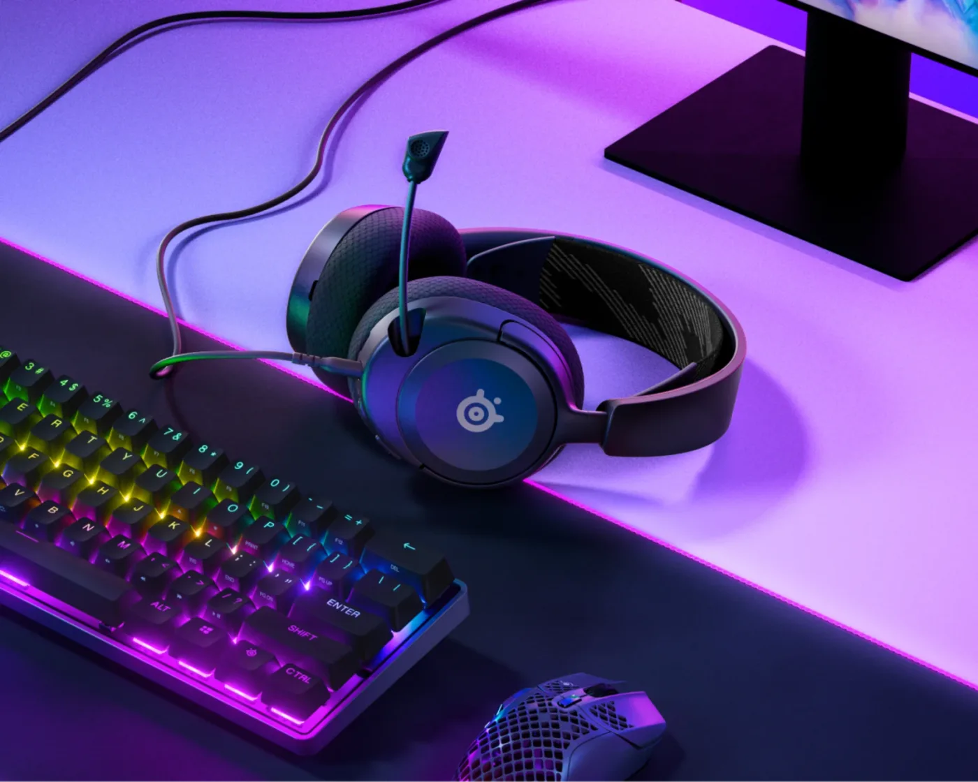 Căștile SteelSeries Arctis Nova 1 lângă tastatură și monitor